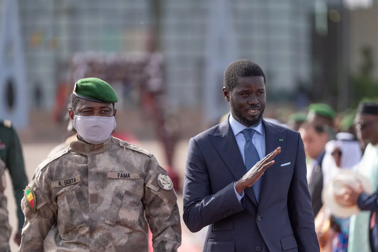 Senegal's President Bassirou Diomaye Faye waves as he walks along with Mali's junta leader Assimi Goita in Bamako