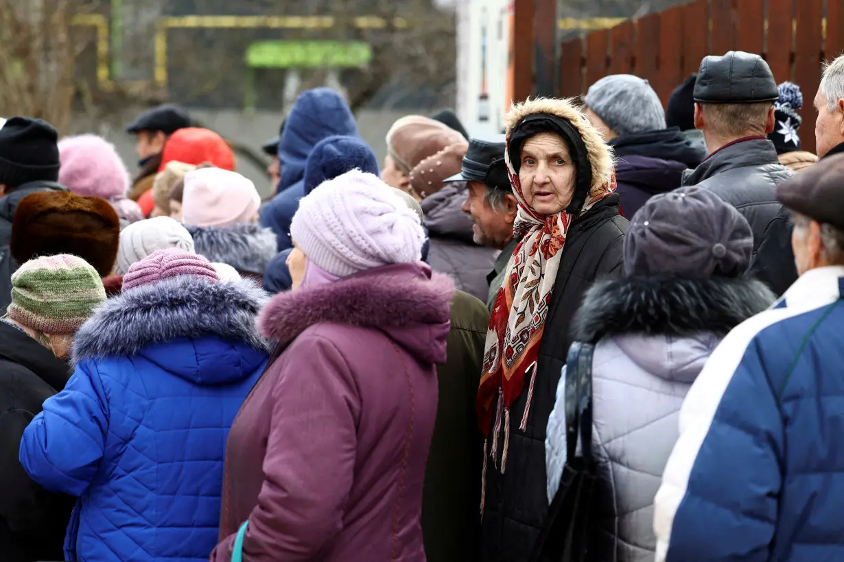 FILE PHOTO: People queue for a meal distribution in Kherson