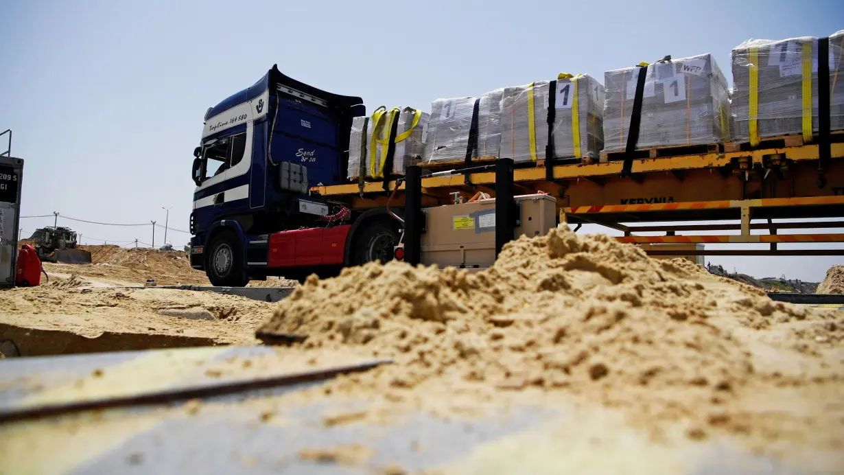 Trucks deliver humanitarian aid over a temporary pier on the Gaza coast