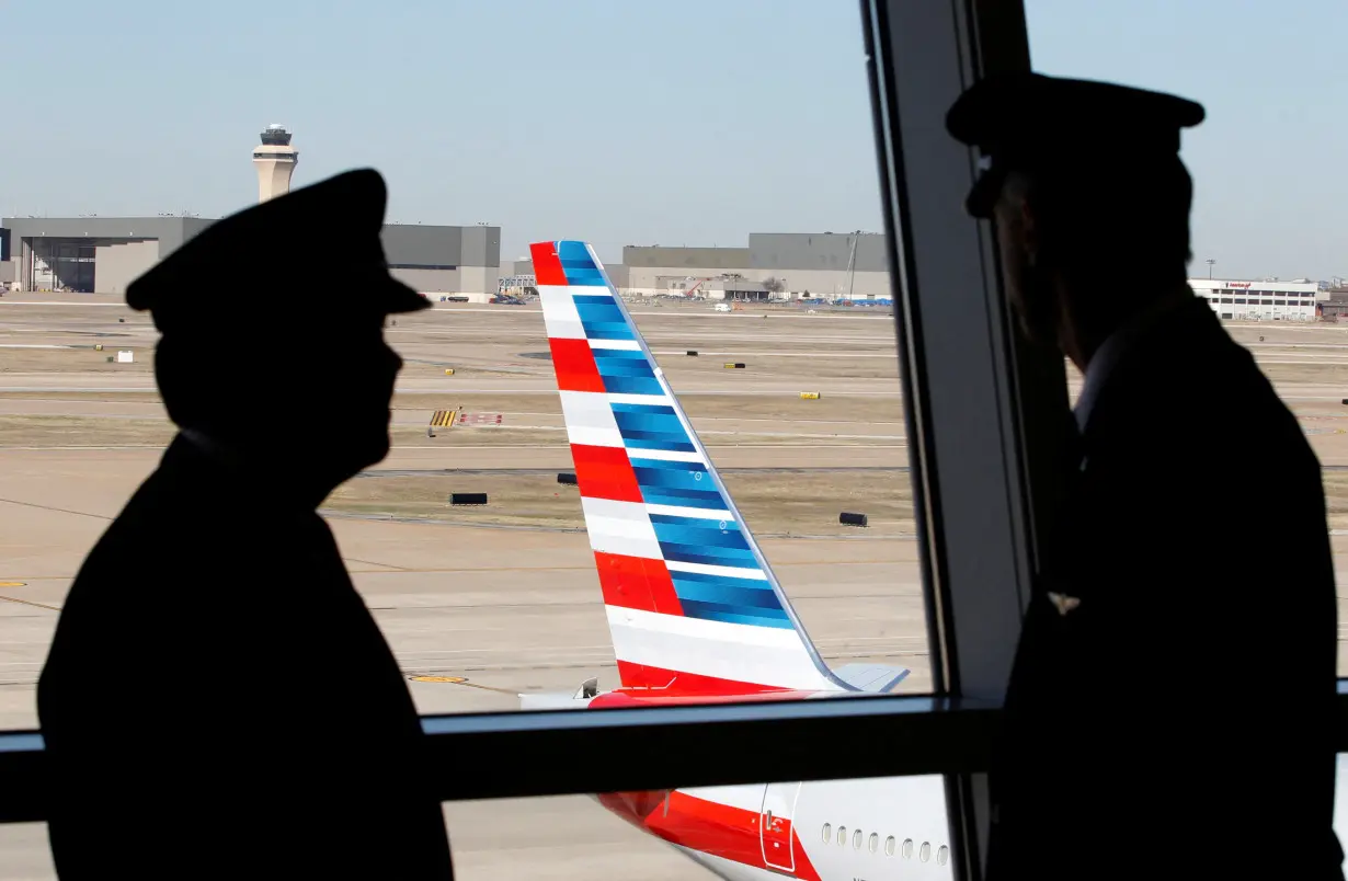 FILE PHOTO: Pilots talk as they look at the tail of an American Airlines aircraft at Dallas-Ft Worth International Airport