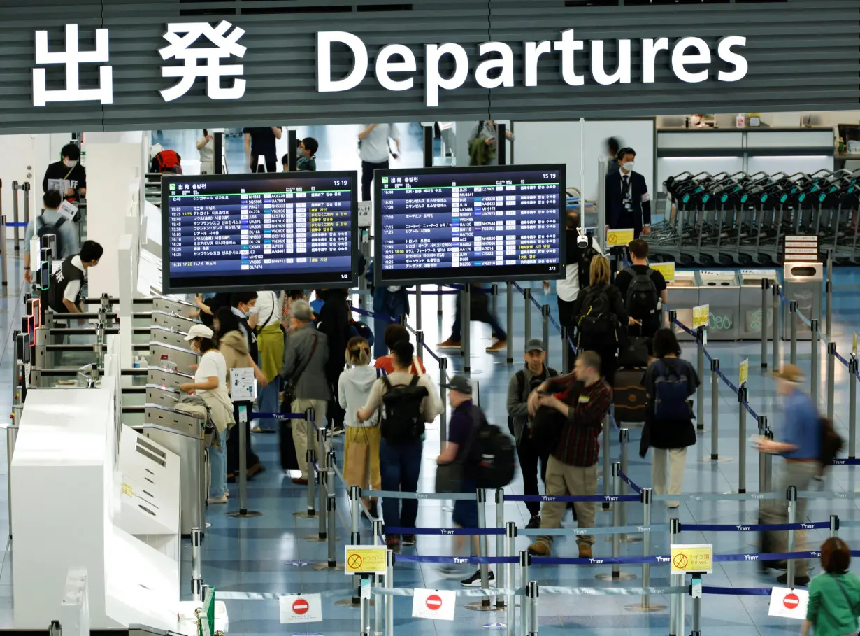 Passengers stand in an international flight departure lobby at Tokyo International Airport