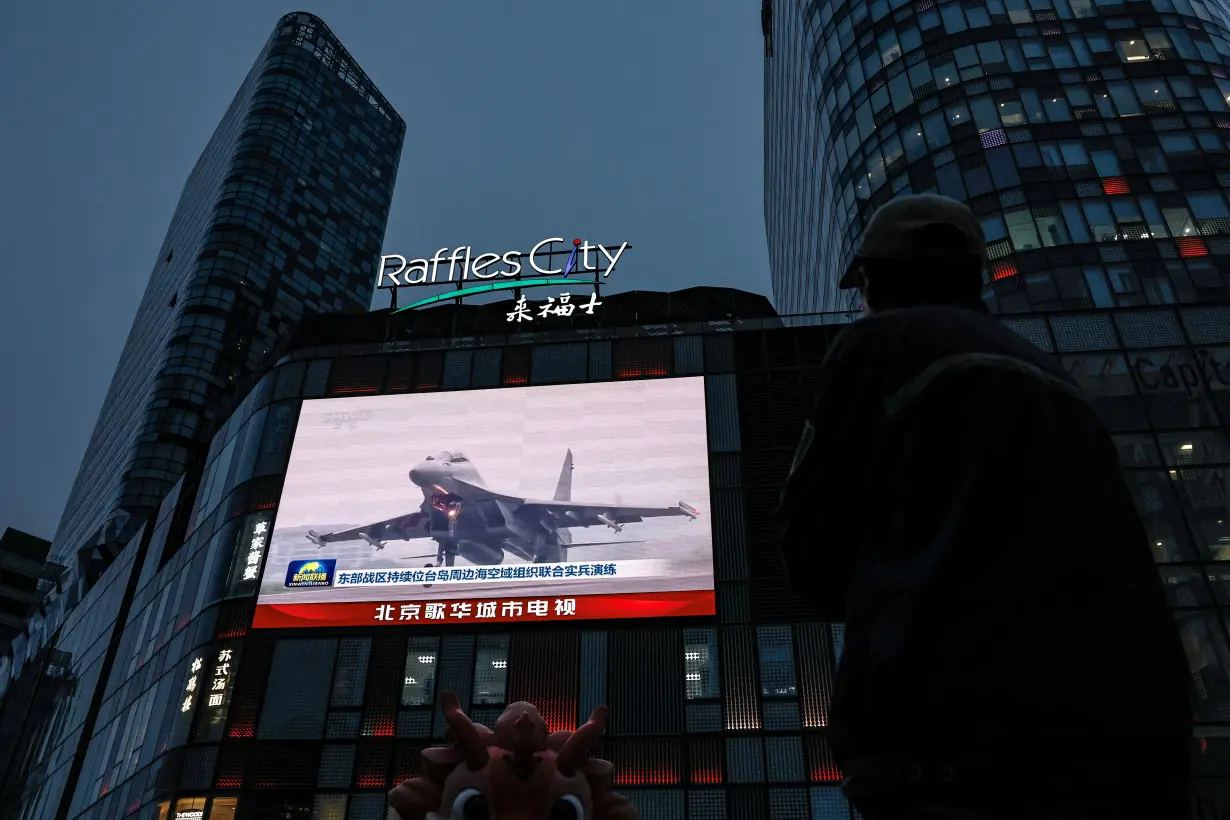 A screen shows news footage of military drills conducted in areas around the island of Taiwan by the Eastern Theatre Command of the PLA in Beijing