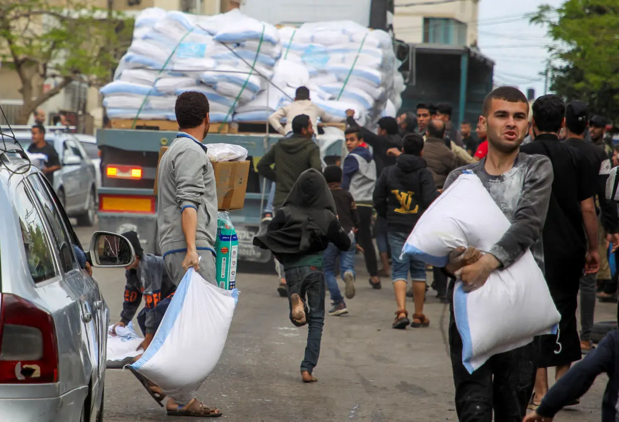 People grab flour bags from a truck after the Israeli military began evacuating Palestinian civilians ahead of a threatened assault on Rafah