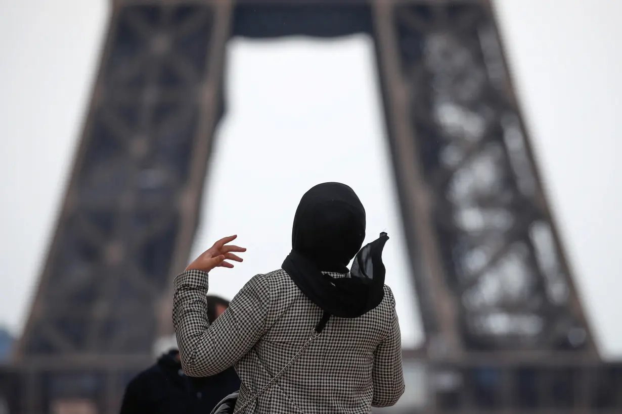 FILE PHOTO: A woman wearing a hijab walks at Trocadero square near the Eiffel Tower in Paris