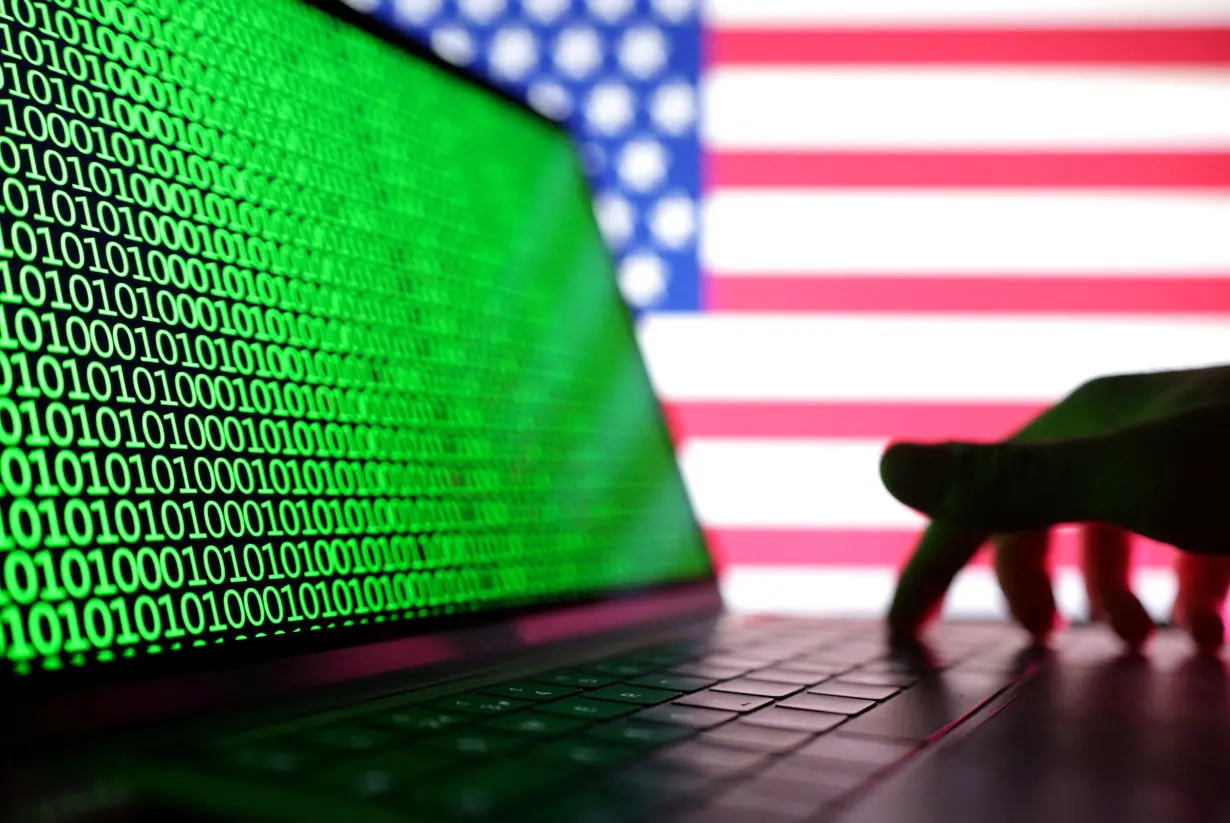 FILE PHOTO: Illustration shows a laptop with binary codes displayed in front of the USA flag