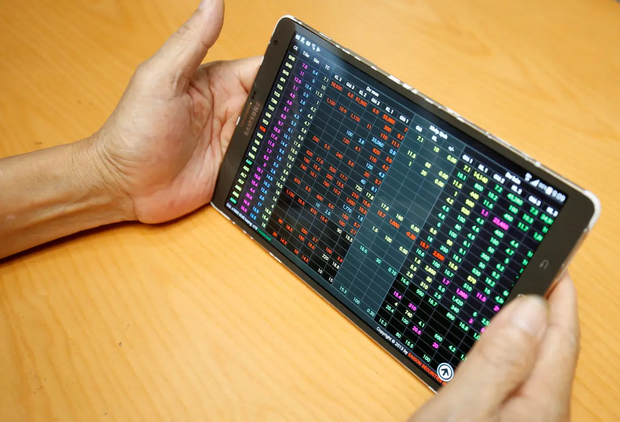 FILE PHOTO: An investor looks at a screen showing stock board at a securities company in Hanoi