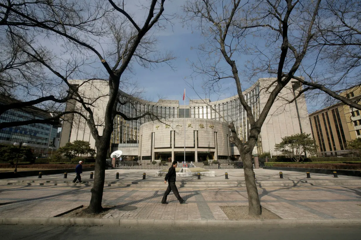 FILE PHOTO: People walk past the headquarters of the central bank of the People's Republic of China in Beijing