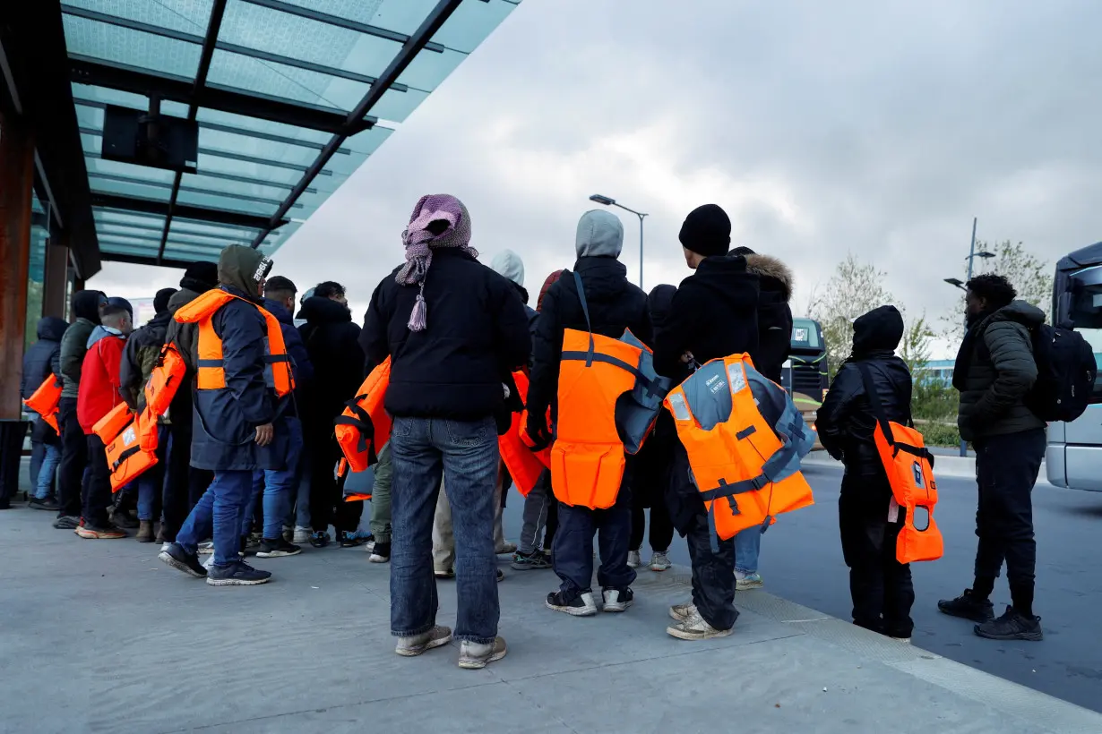 FILE PHOTO: Migrants wait for a bus to return from the beach to their camp, at Calais train station