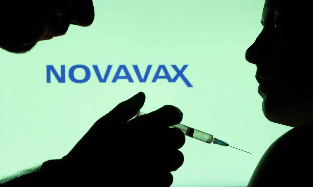 FILE PHOTO: People pose with syringe with needle in front of displayed Novavax logo