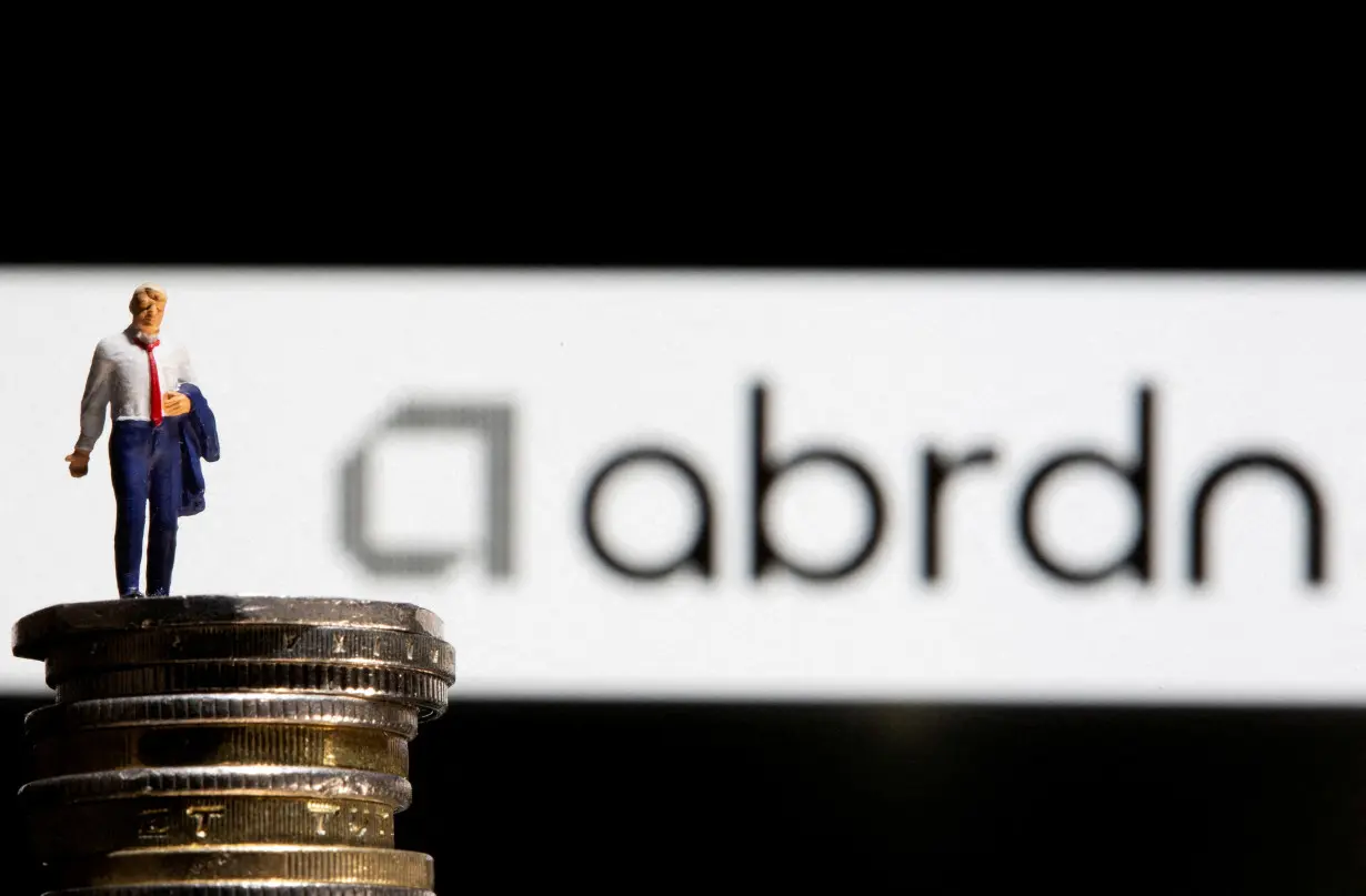 FILE PHOTO: Businessman toy figure is placed on U.K. Pound coins in front of displayed Abrdn logo in this illustration taken