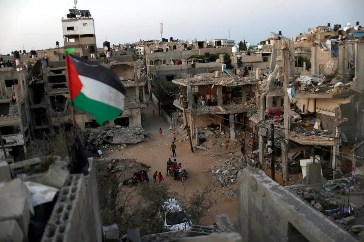 A Palestinian flag flies as the ruins of houses, which were destroyed by Israeli air strikes during the Israeli-Palestinian fighting, are seen, in Gaza