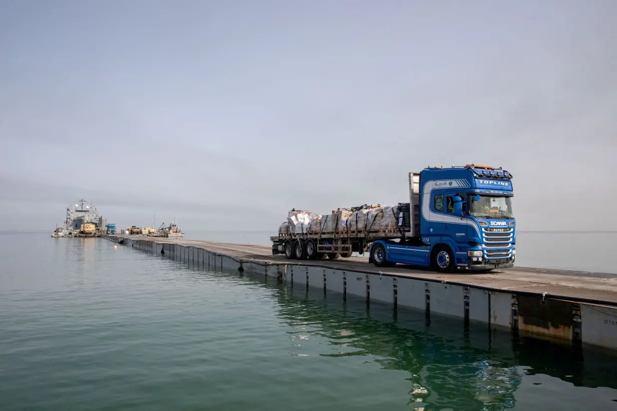 FILE PHOTO: Trucks deliver humanitarian aid over a temporary pier on the Gaza coast