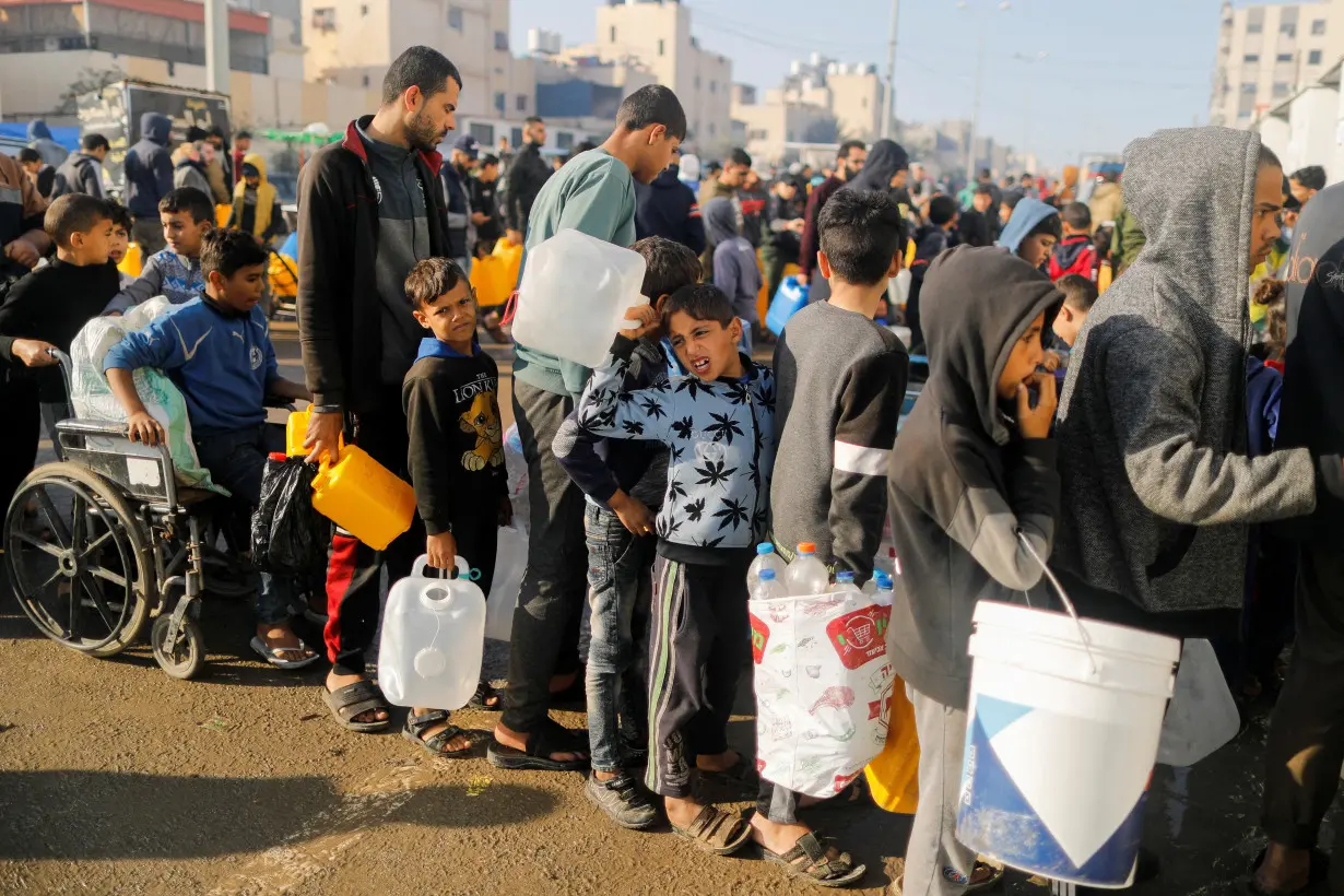 FILE PHOTO: Palestinians queue as they wait to collect drinking water, amid shortages of drinking water, as the conflict between Israel and Hamas continues, in Rafah