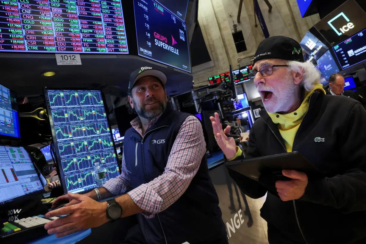 FILE PHOTO: Traders work on the floor at the New York Stock Exchange (NYSE) in New York City
