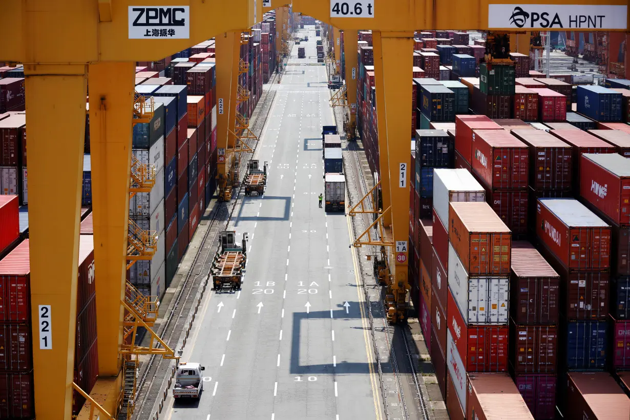 A truck driver stands next to his truck as he gets ready to transport a shipping container at Pusan Newport Terminal in Busan