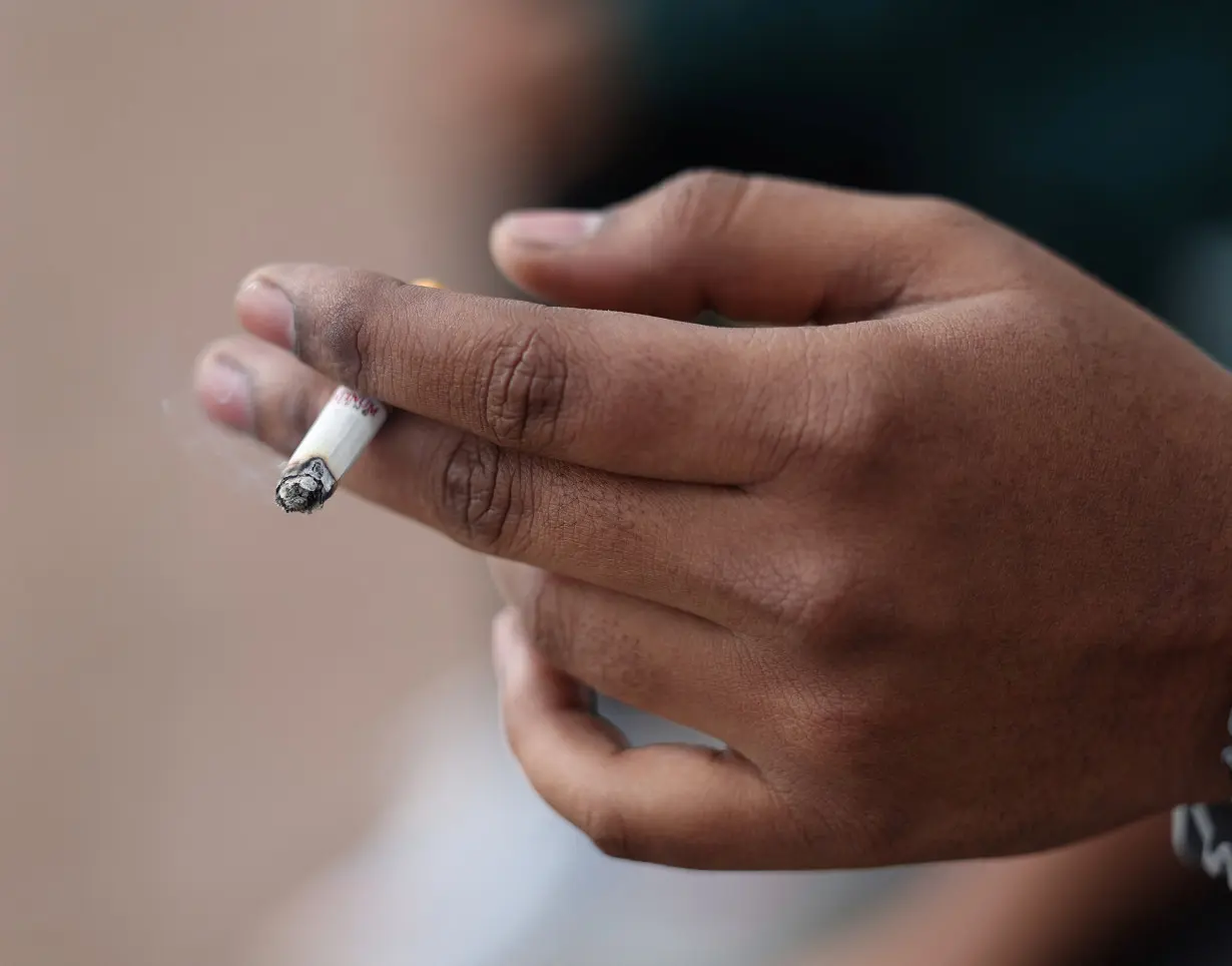 A man holds his cigarette as he smokes in London