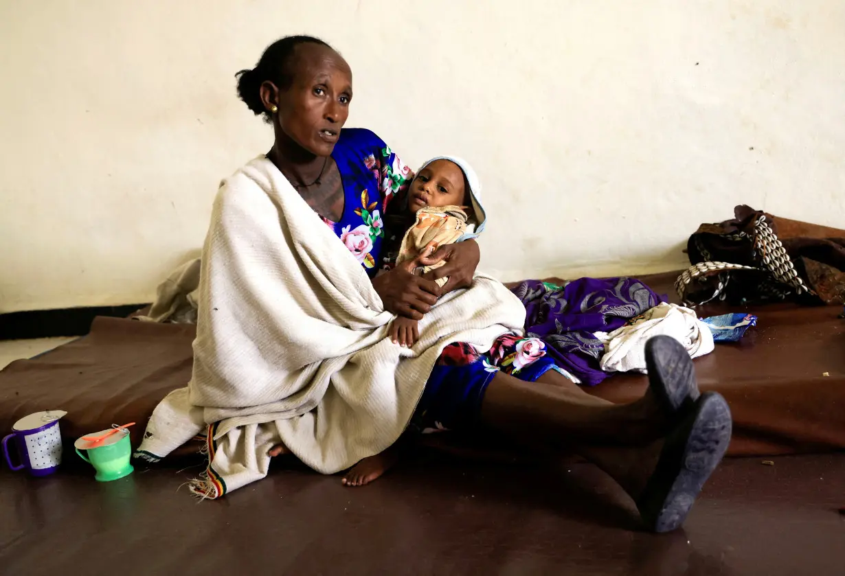 FILE PHOTO: Maeru Adugna, 45 carries her severely malnourished son, at the Samre Hospital in Samre town