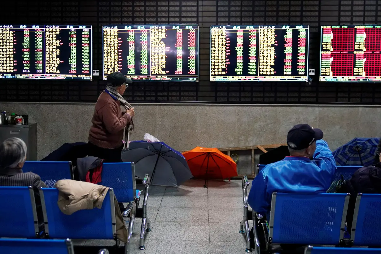 Investors look at screens showing stock information at a brokerage house in Shanghai