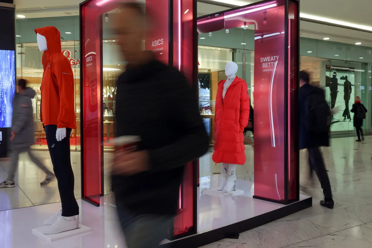 People walk past mannequins in a shopping centre