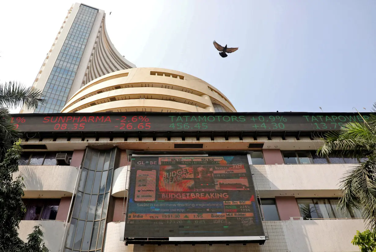 FILE PHOTO: A bird flies past a screen displaying the Sensex results on the facade of BSE building in Mumbai