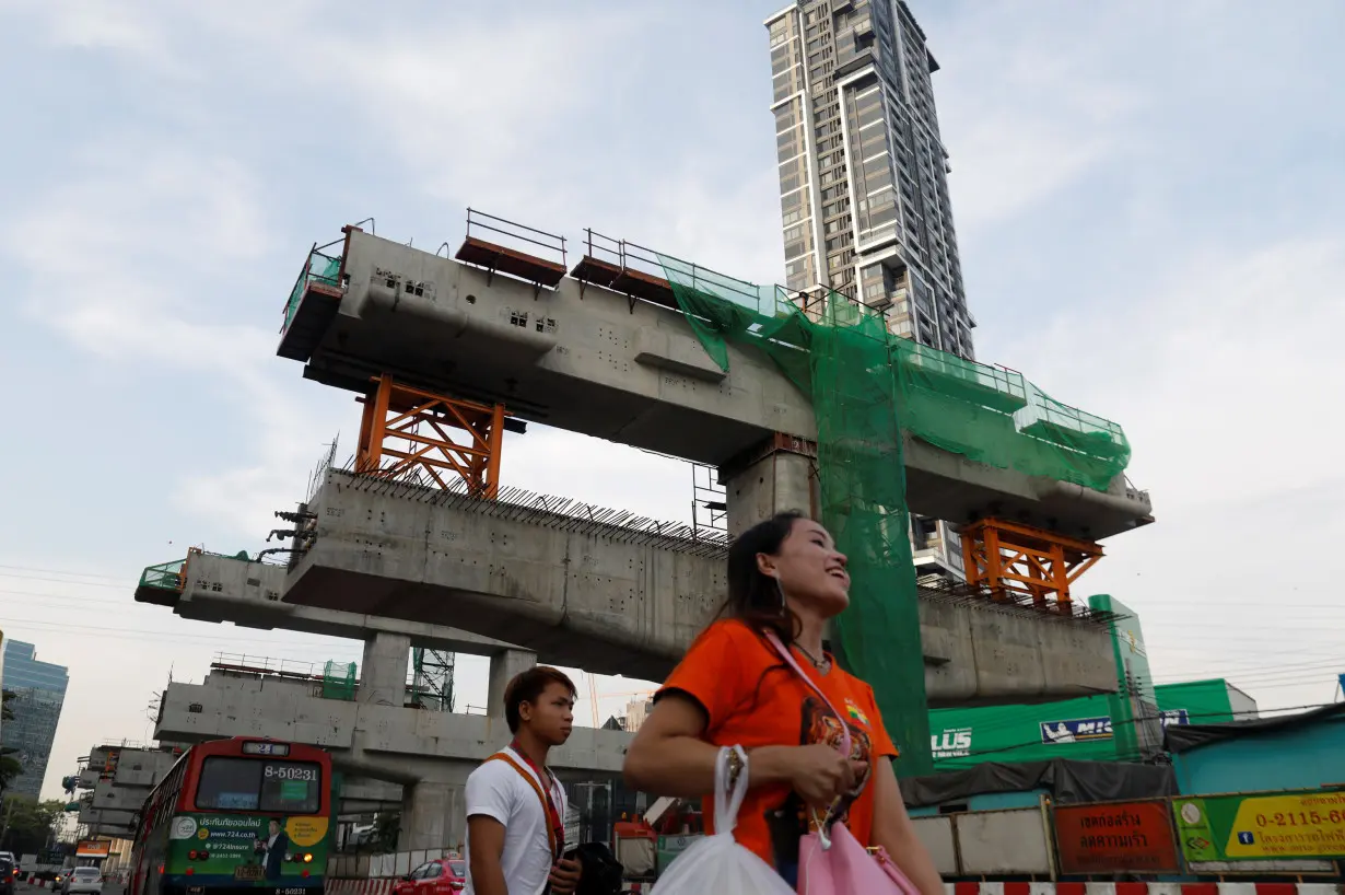 People walk past Skytrain construction site in Bangkok