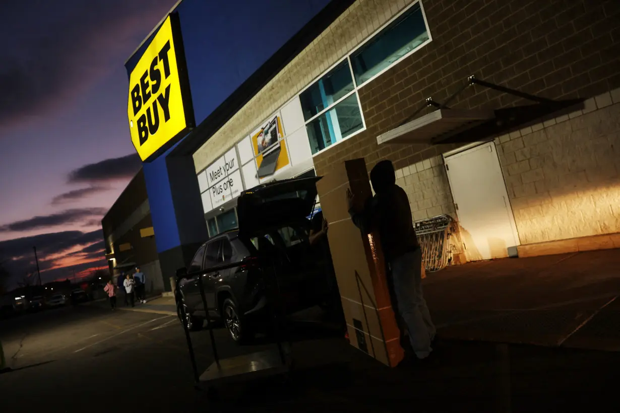 An employee at Best Buy electronics store helps load a television after a shopper made a purchase during Black Friday deals in Westbury