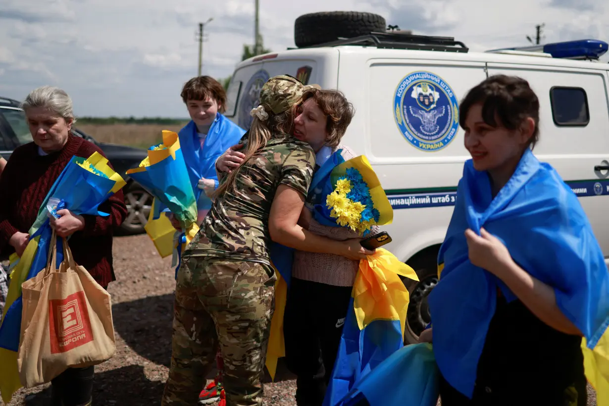 Ukrainian military officer embraces civilians and POWs after a swap at an undisclosed location in Ukraine