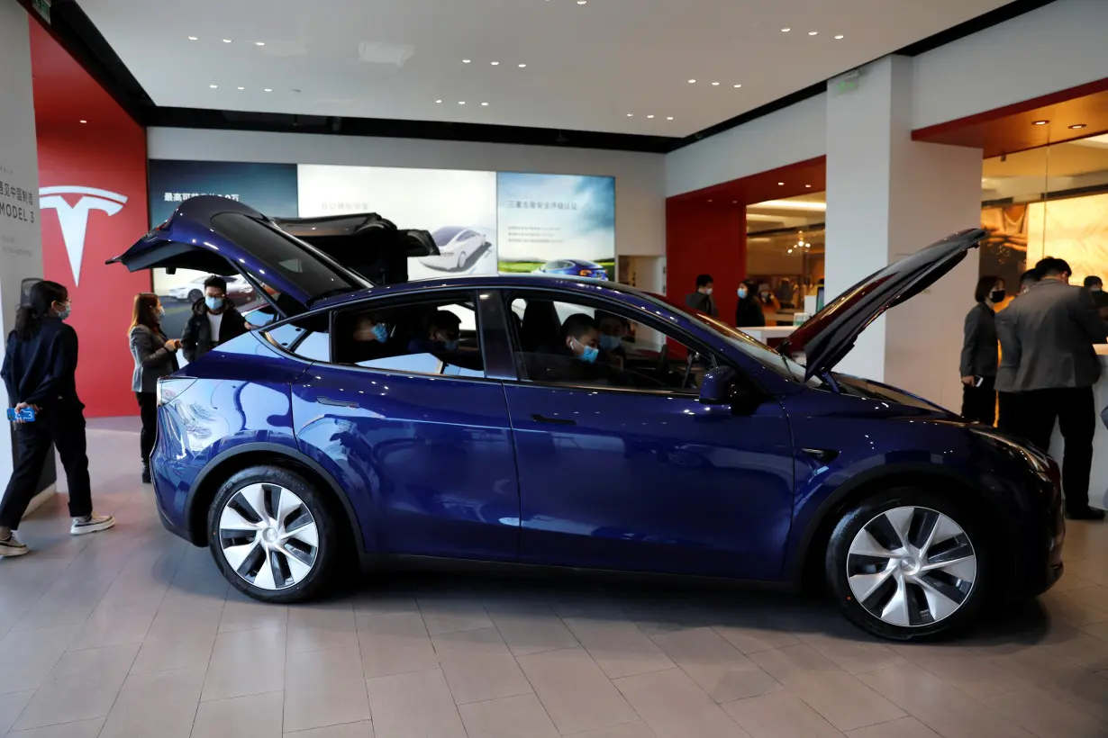 FILE PHOTO: Visitors check a China-made Tesla Model Y sport utility vehicle (SUV) at the electric vehicle maker's showroom in Beijing