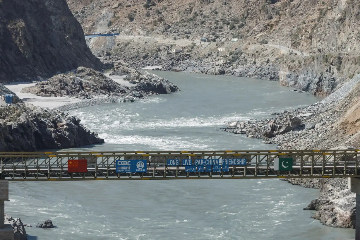 FILE PHOTO: View of a bridge with China and Pakitan's flag over the River Indus near the site of the Dasu Dam, near Dasu