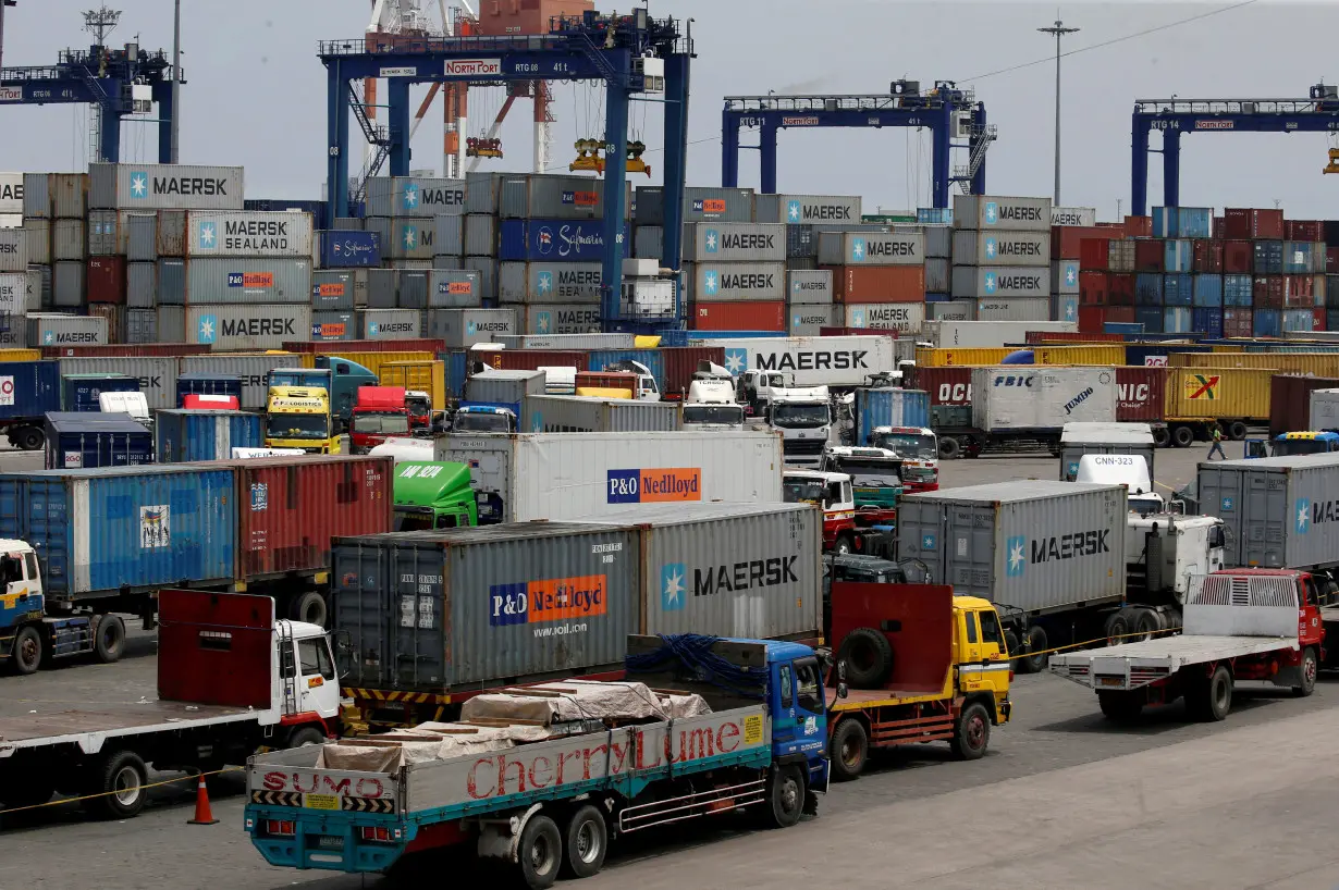 Trucks transporting containers with imported items are prepared to leave a port in Manila