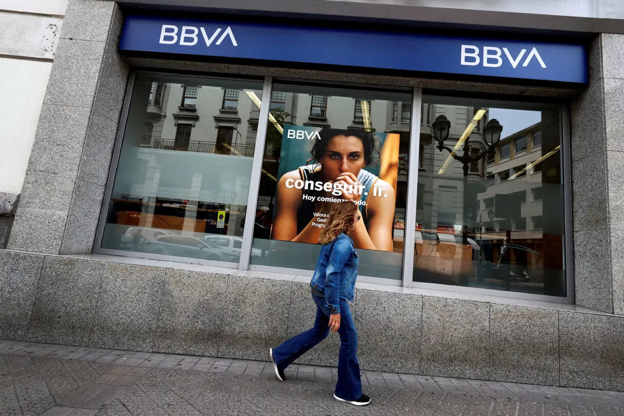 FILE PHOTO: A woman walks past a branch of Spain's BBVA bank in Bilbao