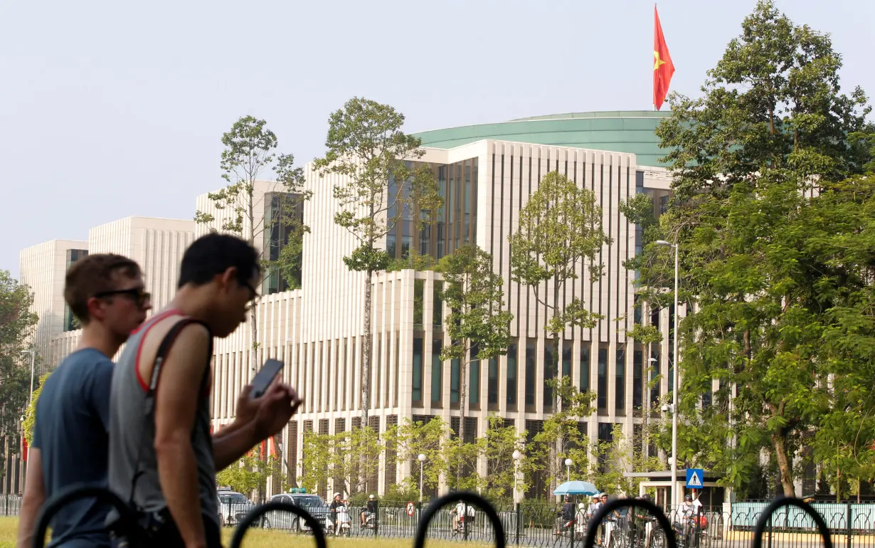 Tourists walk past Vietnam's National Assembly (Parliament) building in Hanoi, Vietnam