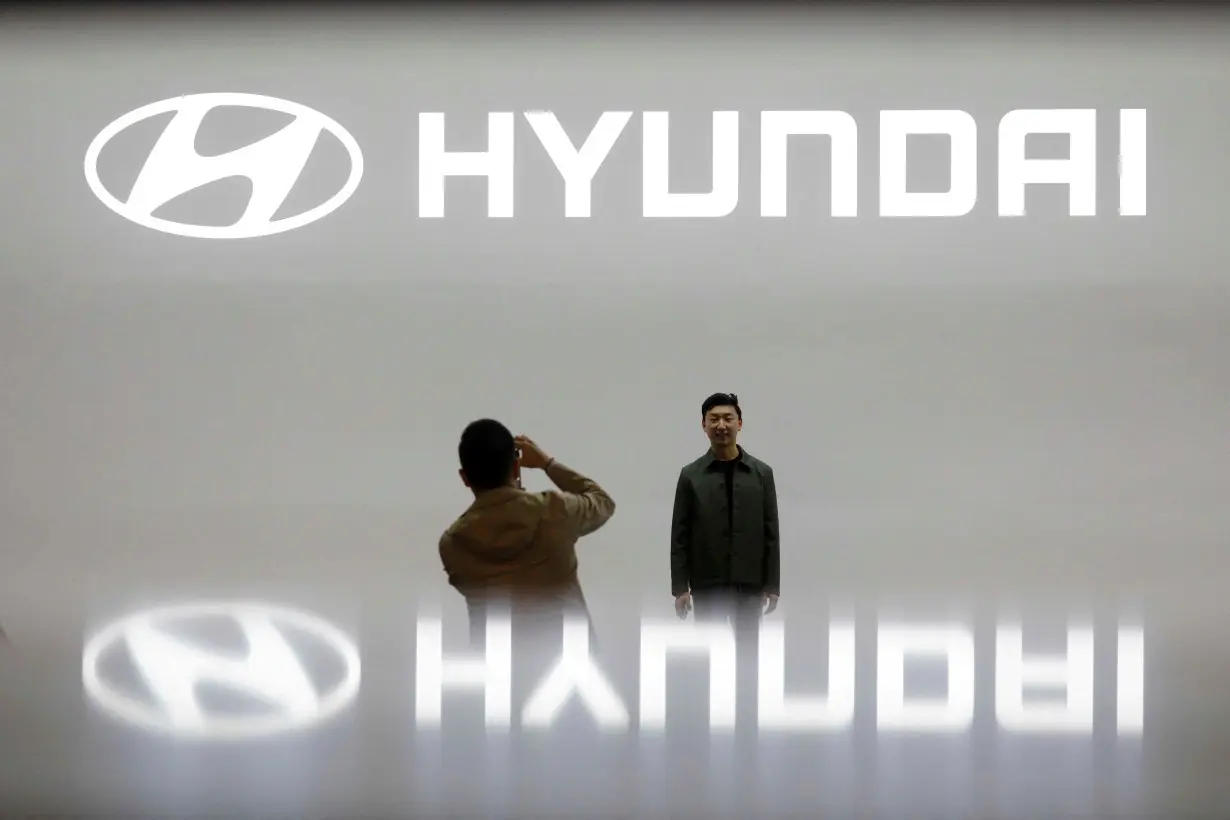 FILE PHOTO: Visitors take photographs in front of the logo of Hyundai Motor during the 2019 Seoul Motor Show in Goyang