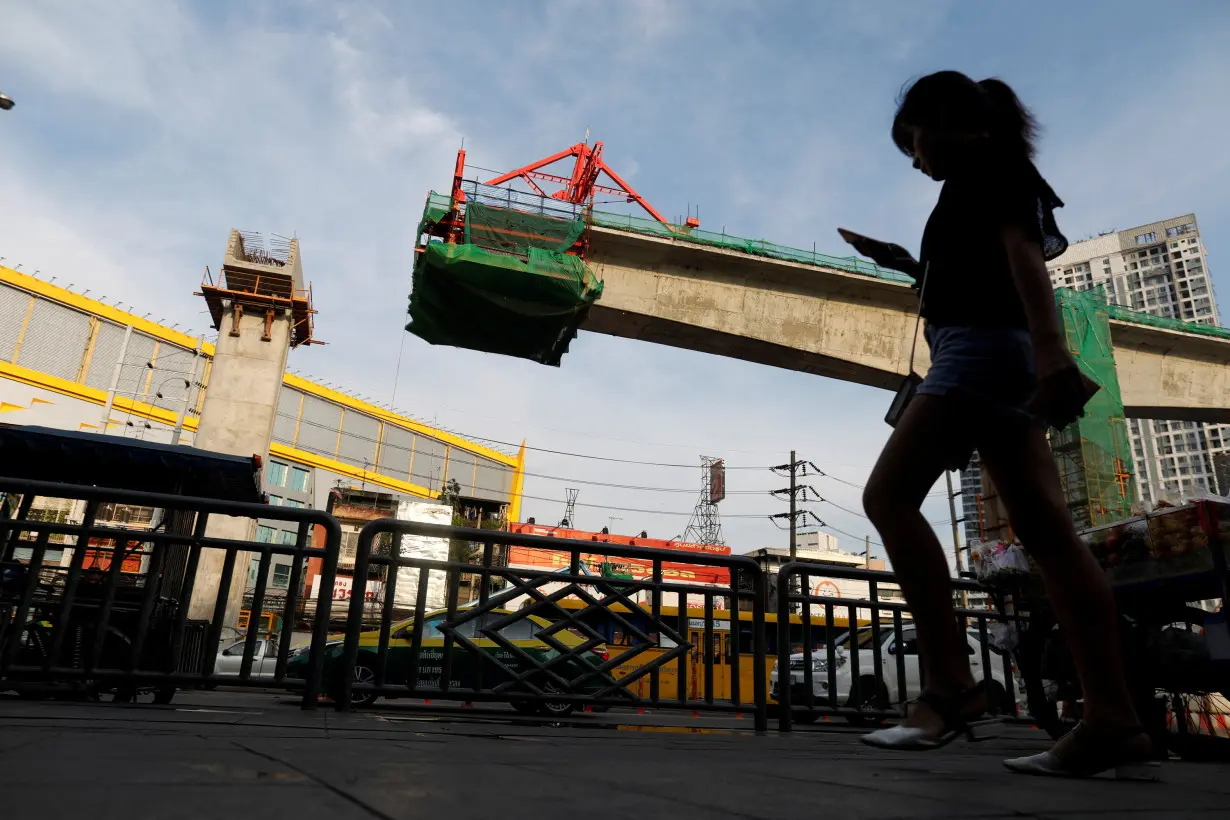 FILE PHOTO: Girl walks past Skytrain construction site in Bangkok