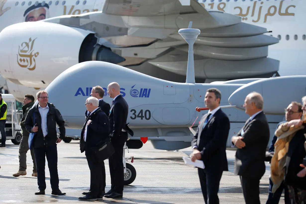 Visitors stand in front of an Heron TP drone at the ILA Air Show in Berlin