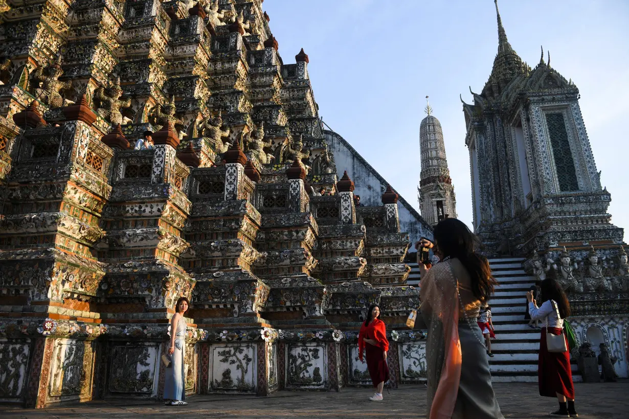 Tourists dressed in traditional Thai costumes visit Wat Arun temple in Bangkok