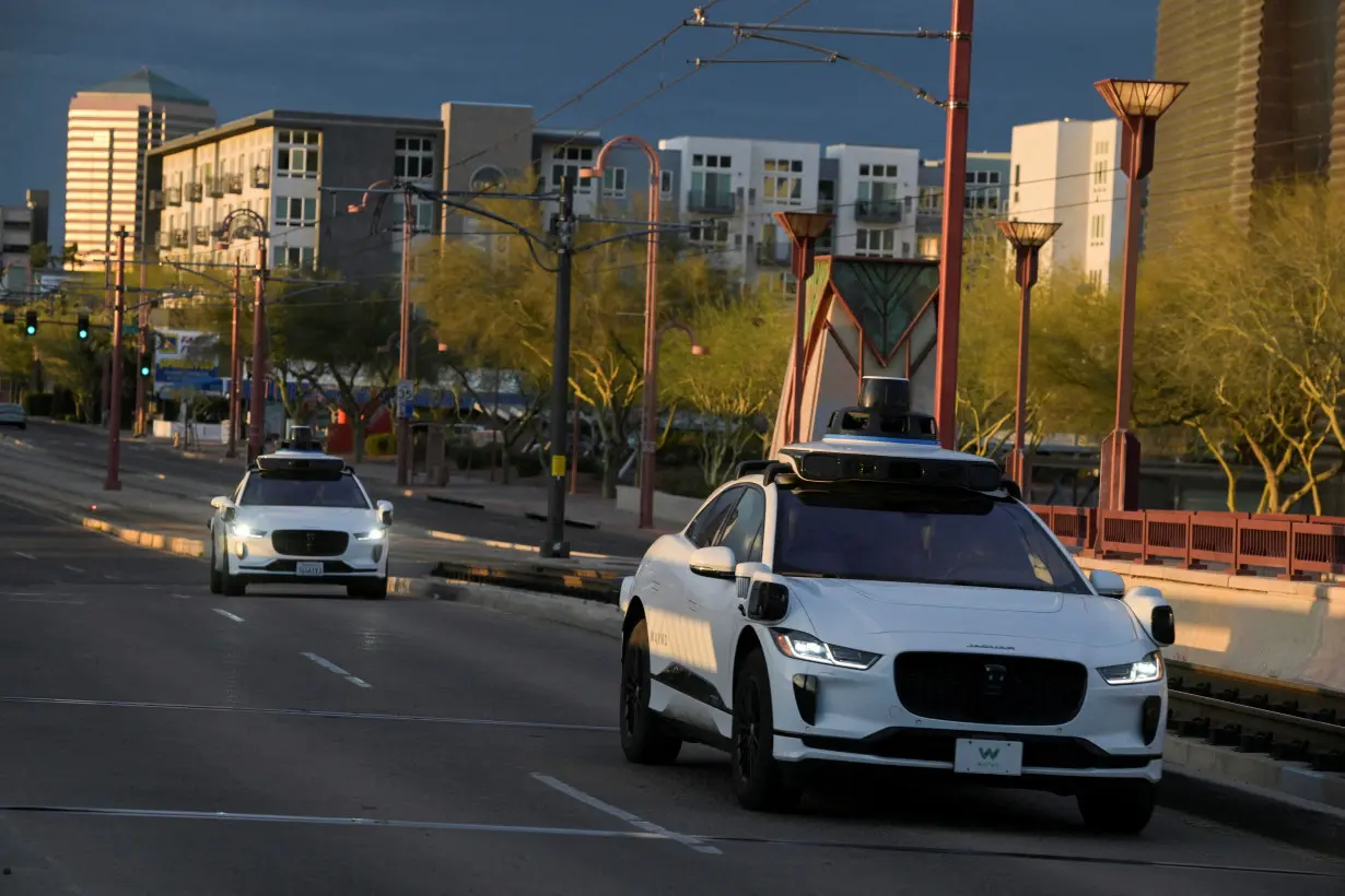 FILE PHOTO: Two Waymo autonomous vehicles drive themselves down Central Avenue in Phoenix, Arizona