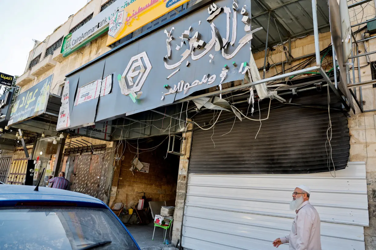 A man walks past a closed exchange office building that was damaged and targeted during an Israeli military operation, in Tulkarm