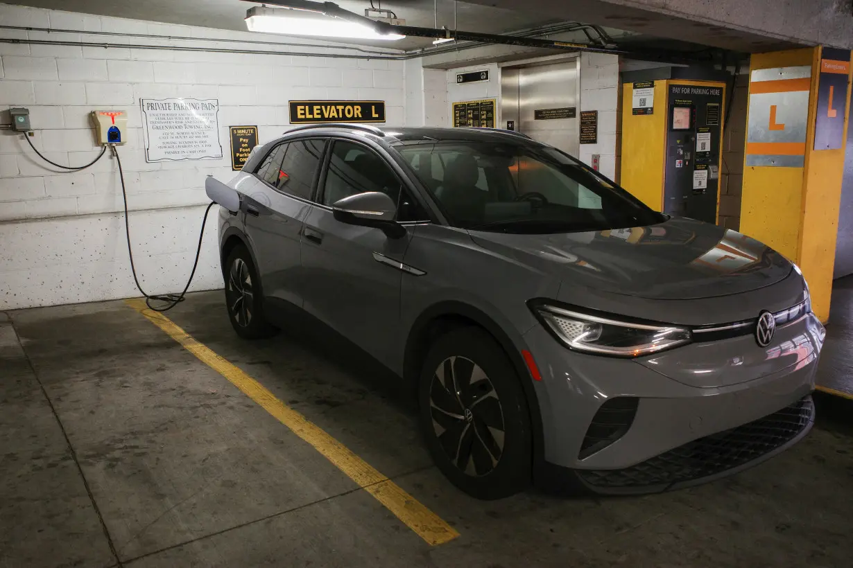 A Volkswagen ID.4 electric vehicle charges at an EV charging station inside a parking garage owned by the City of Baltimore