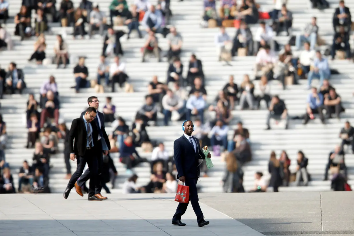 Businessmen enjoy the good weather at lunch time under the Arche de la Defense, in the financial district west of Paris, as warm and sunny weather continues in France