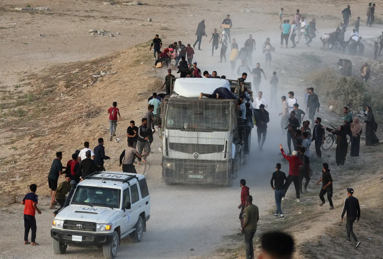 Palestinians climb on a truck to grab aid that was delivered into Gaza through a U.S.-built pier, as seen from central Gaza Strip