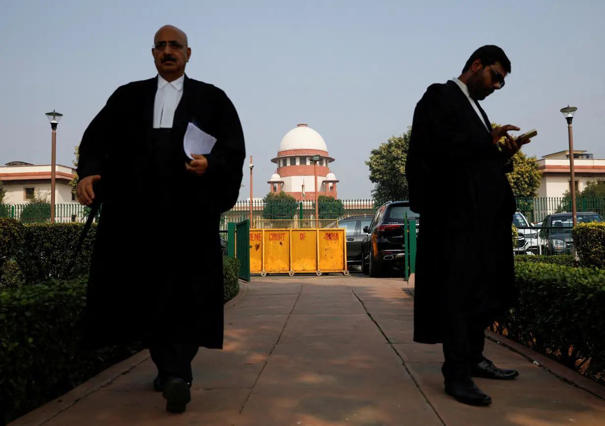 FILE PHOTO: A lawyer looks into his mobile phone as another walks past, in front of India's Supreme Court in New Delhi