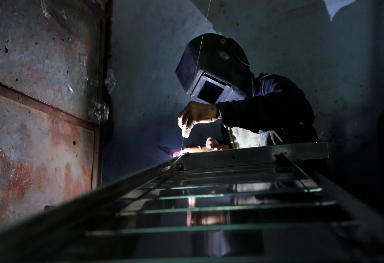 A worker welds steel pipes to make a counter at a steel furniture manufacturing unit in Ahmedabad