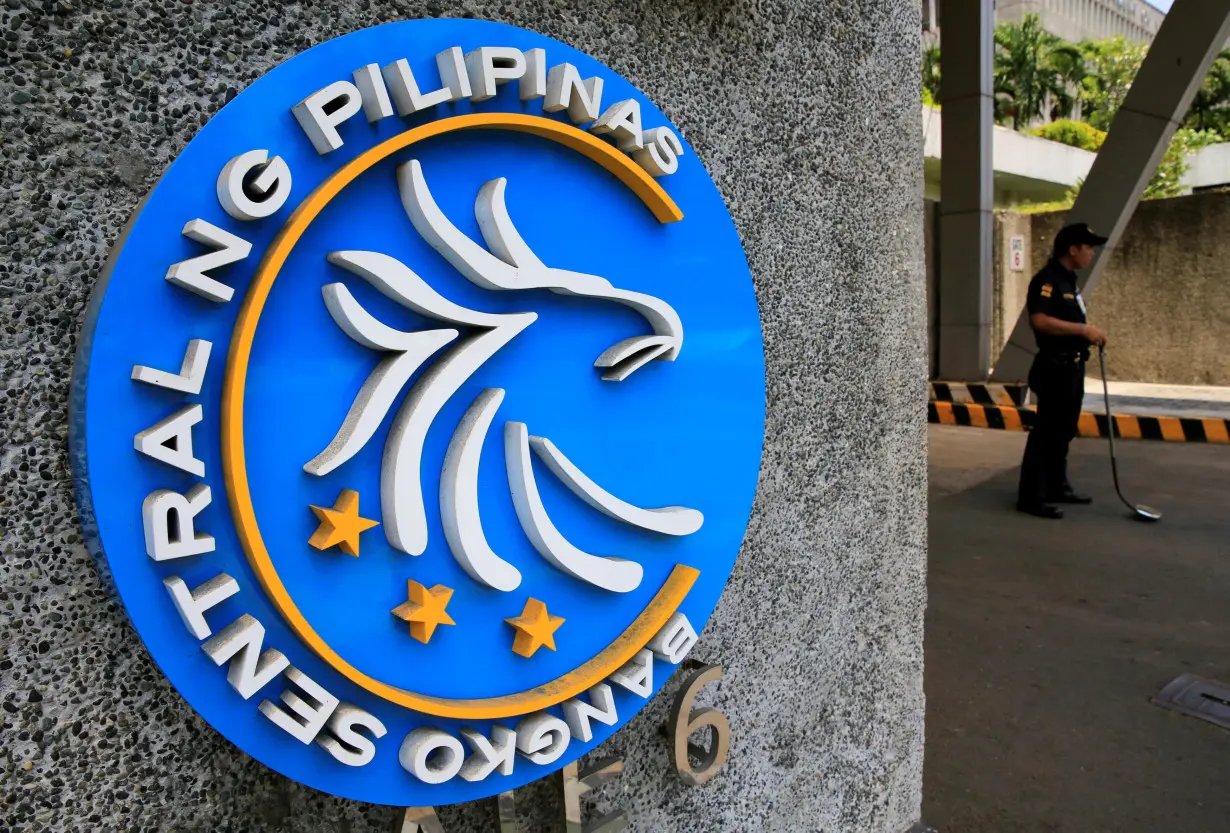 FILE PHOTO: Security guard stands beside a logo of the Bangko Sentral ng Pilipinas (Central Bank of the Philippines) posted at the main gate in Manila