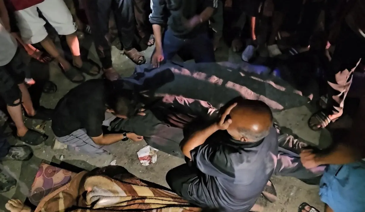 Palestinians react next to bodies of people killed in an Israeli strike on a school sheltering displaced people in Nuseirat refugee camp in the central Gaza Strip