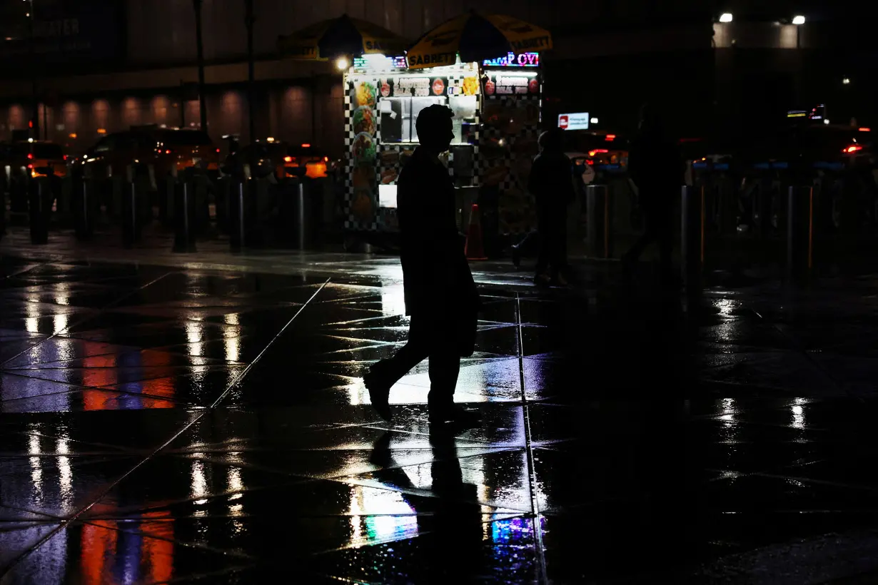 A man walks in silhouette during rainy weather across Pennsylvania Station in New York City