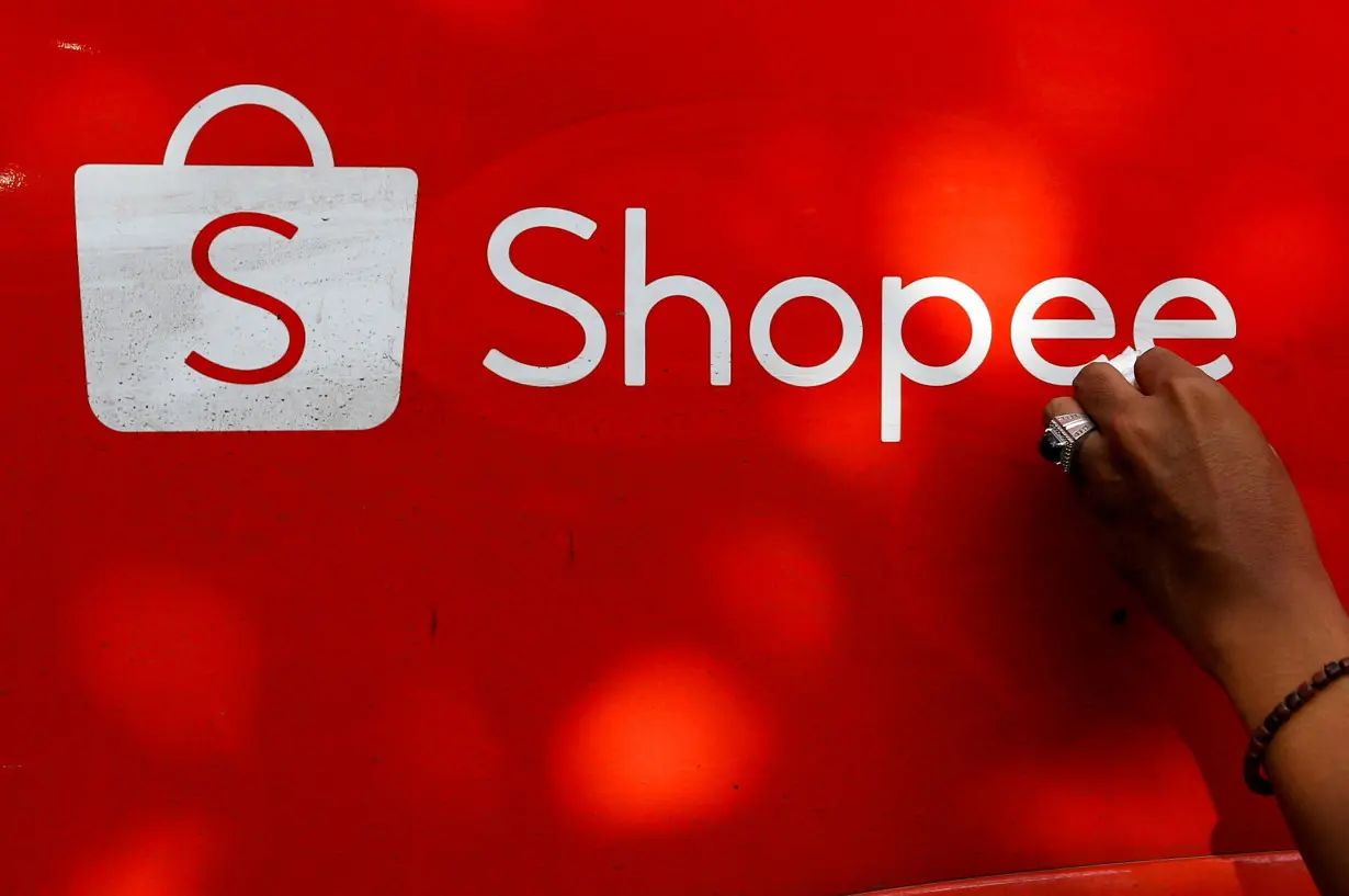 FILE PHOTO: A worker wipes the door of a car with the sign of Shopee, an Indonesian e-commerce platform, in Jakarta