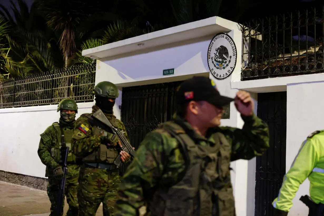 Police and military officials walk outside the Mexican embassy from where they forcibly removed the former Ecuador Vice President Jorge Glas in Quito