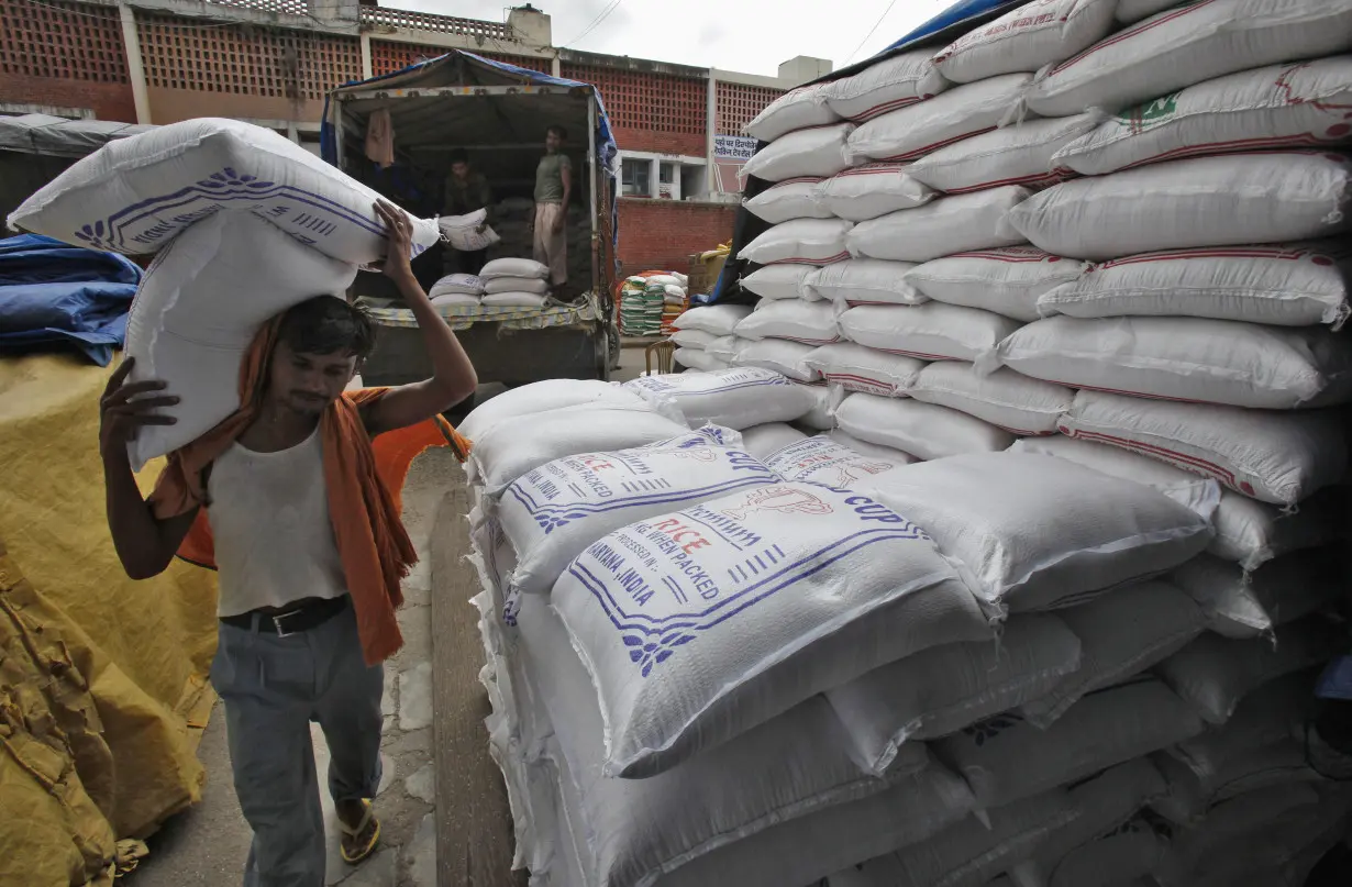 A labourer unloads sacks filled with rice at a wholesale grain market in Chandigarh