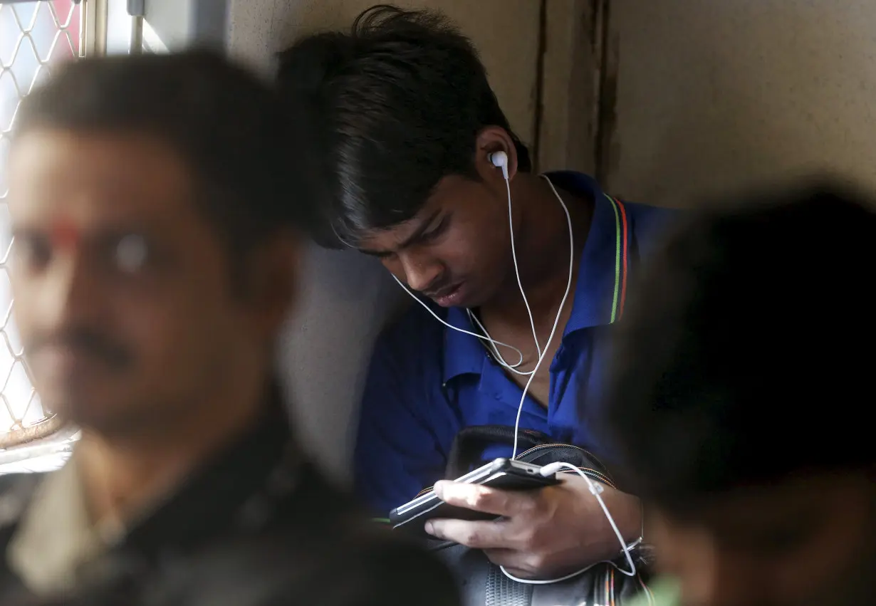 A man watches a video on his mobile phone as he commutes by a suburban train in Mumbai